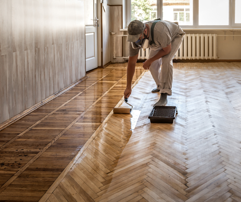 Craftsman rolling a fresh coat of varnish across a herringbone hardwood floor